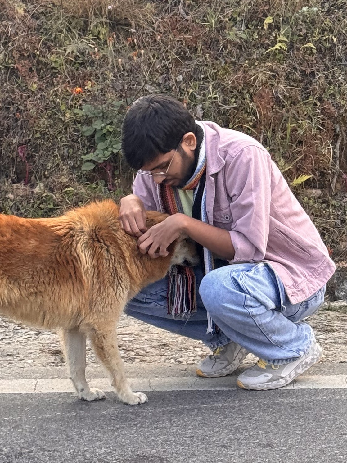 Aakash Reddy petting a dog by a hillside